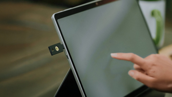 Person inserting YubiKey security device into laptop USB port